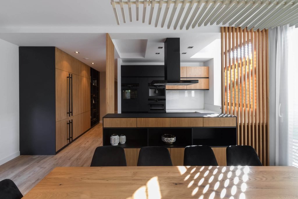 open space con cucina nera con dettagli design in legno naturale